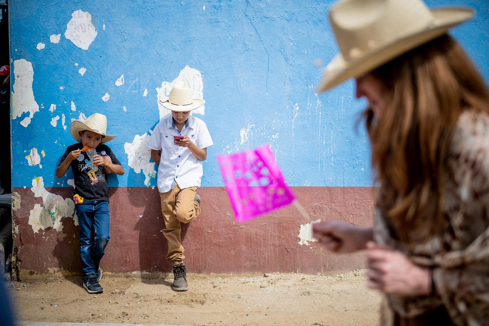 two boys stand by as a mezcal palanque dedication parade passes